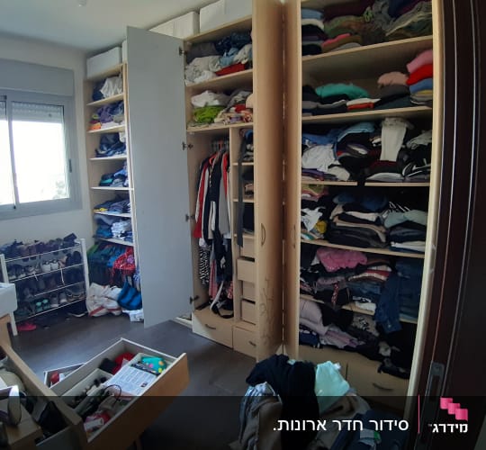 ארון בגדים פתוח עם מדפים מלאים בבגדים מקופלים